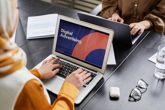 Two professionals work on laptops focusing on digital advertising in an office setting.